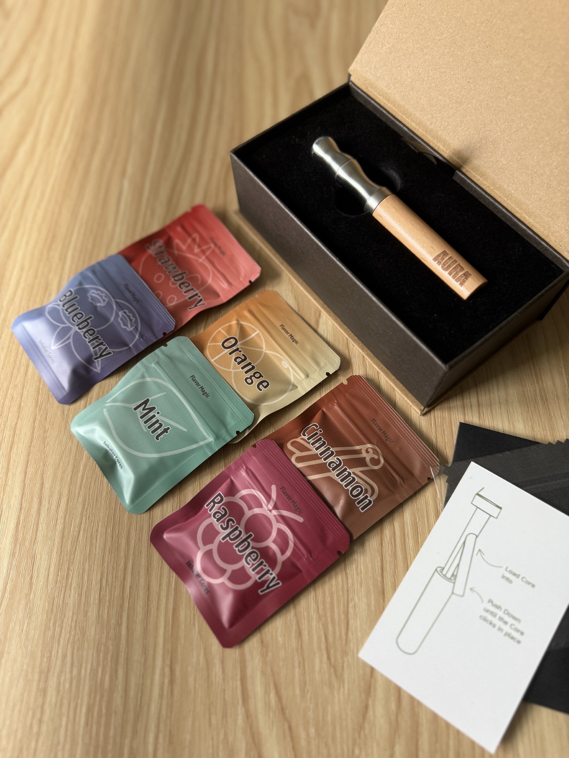 Assorted flavour pods for a flavoured Air device on a wooden surface with packaging and instructions.
